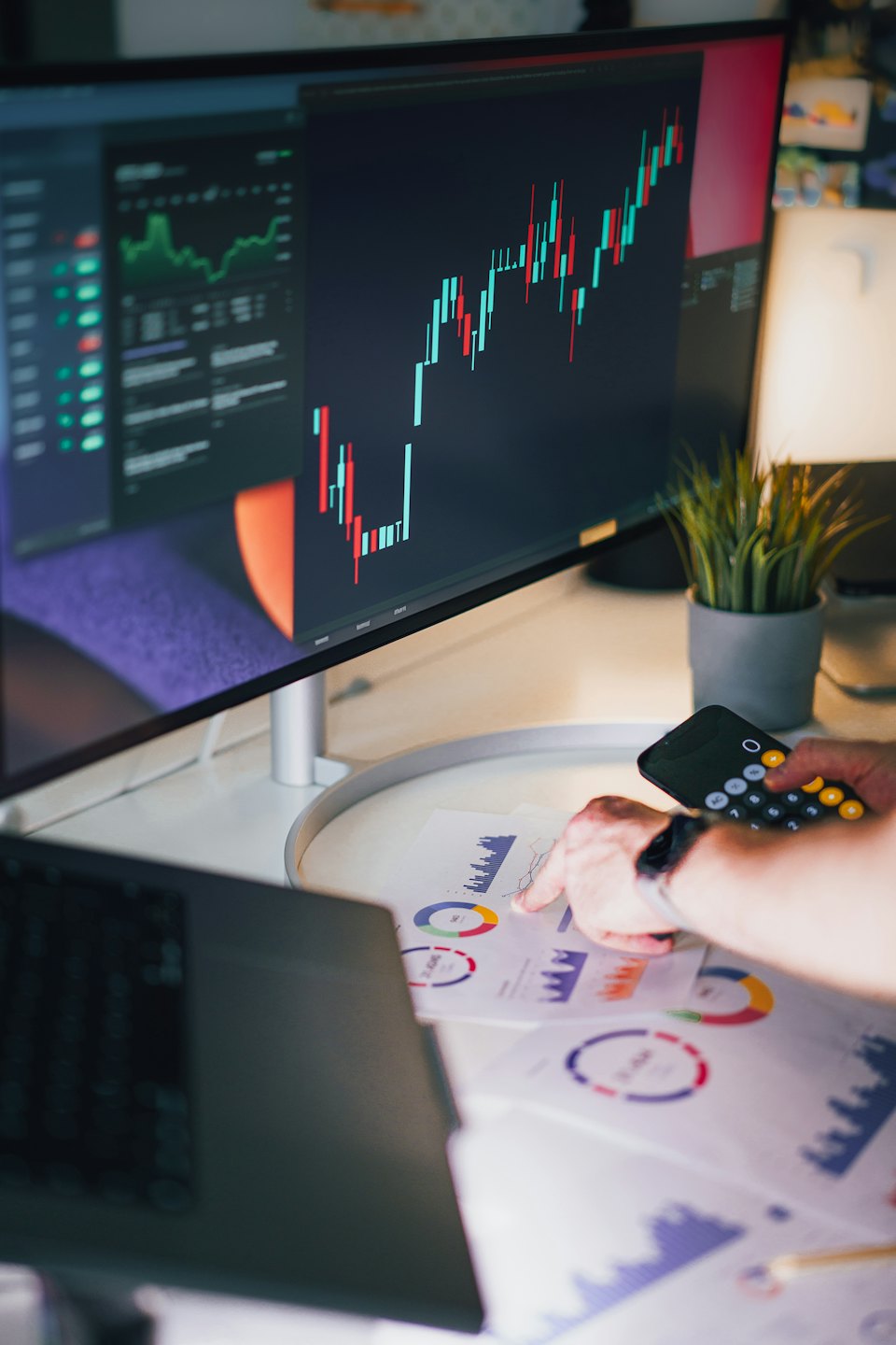 Une personne analyse des graphiques de données financières sur un bureau blanc.